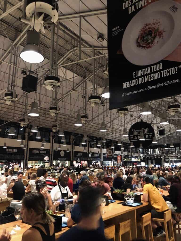 Inside Time Out Market Lisbon with people dining at long communal tables