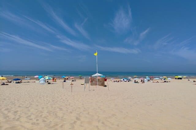 Parasols and yellow flag at Costa da Caparica beach in Portugal