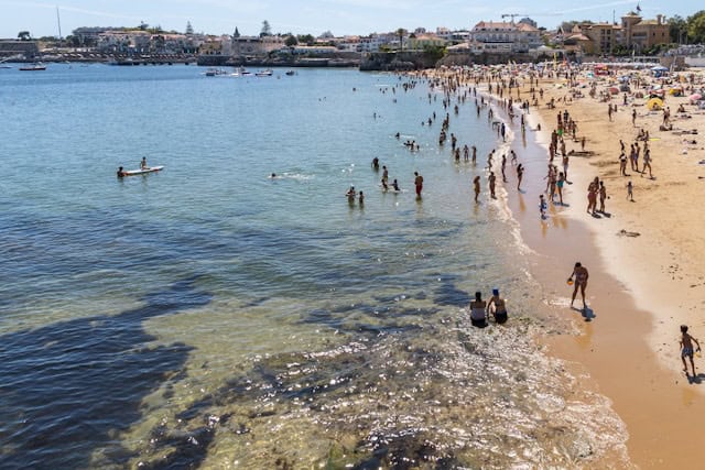 View of people on Praia da Duquesa  beach near Lisbon, swimming and paddling 