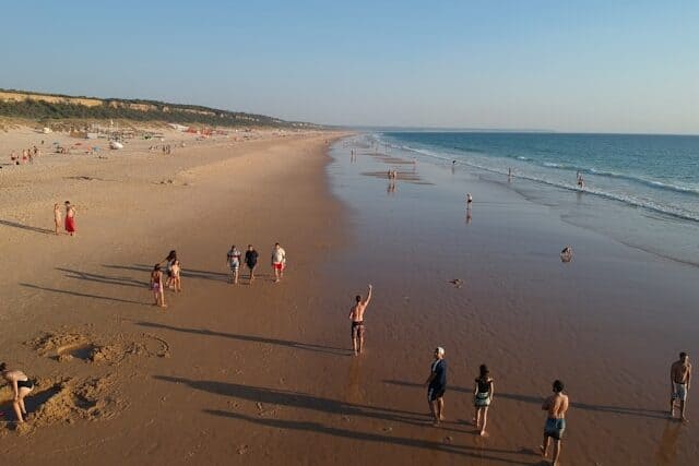 People walking on the wide beach at Costa da Caparica.