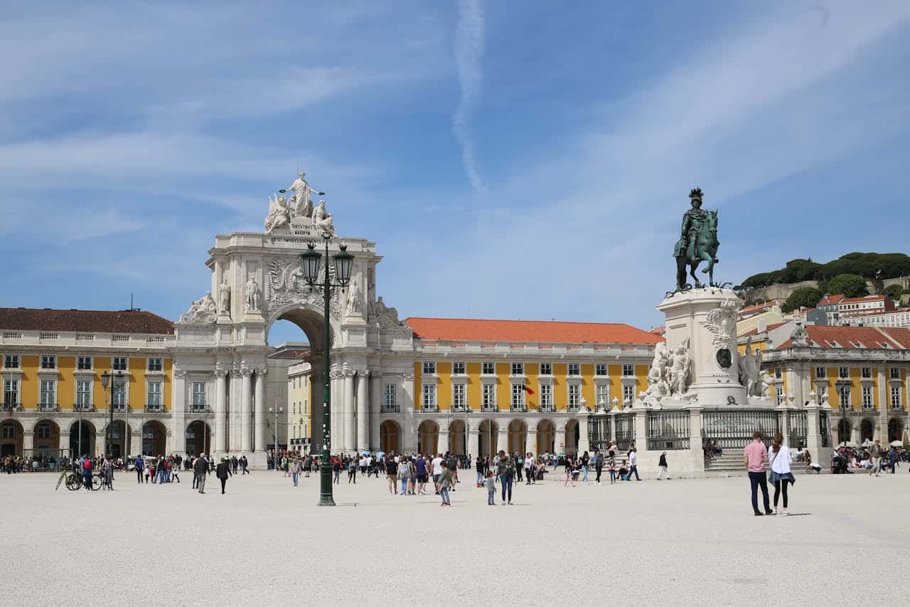 People walking around Praça do Comércio in Lisbon with the equestrian statue of King José I and Arco da Rua Augusta in the background