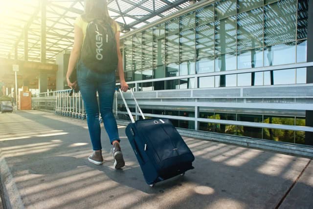 Young woman arriving at Lisbon Portela International Airport with luggage